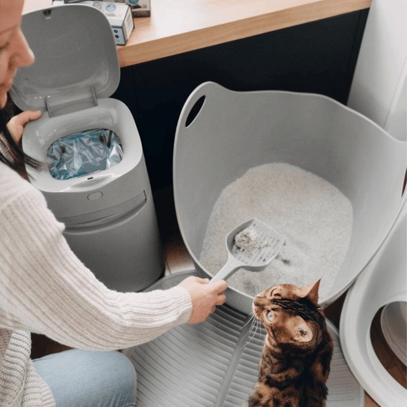 Imagen una mujer con su gato limpiando Litter Genie